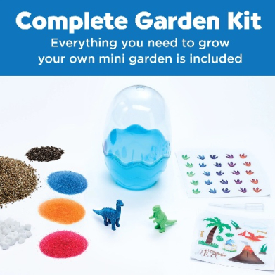 Complete Garden Kit demo: blue water-filled container, colorful powder pigments, tiny dinosaur figures, and sticker sheets on a white surface.