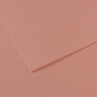 Close-up of light pink textured paper with a folded corner and layered edges.