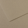 Two overlapping sheets of brown kraft cardboard on a light tan surface (close-up).