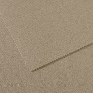 Two overlapping sheets of brown kraft cardboard on a light tan surface (close-up).