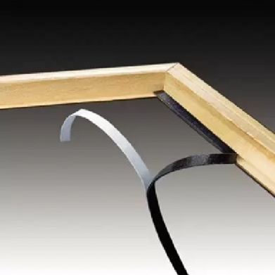 Close-up of a wooden picture frame corner with silver and black metal braces providing support along the edge.